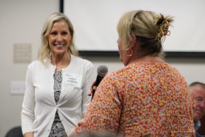 Woman with microphone, woman in background smiling